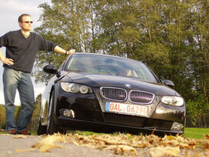 Man leaning next to black car during a test drive.